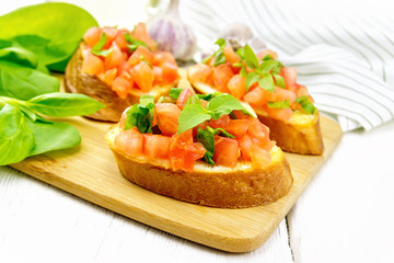Bruschetta with tomato and spinach on white table