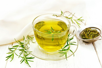 Tea of rosemary in cup with napkin on light board
