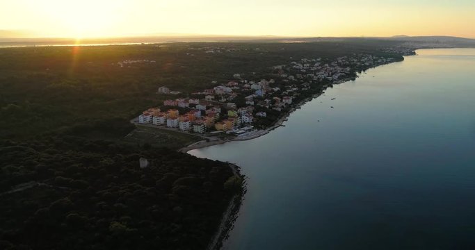 City on the croatian shore, C4k aerial, descending, drone shot, of Kozino town on the mediterranean coast, on the adriatic sea, near Zadar city, on a sunny, sunrise, summer dusk, in Croatia