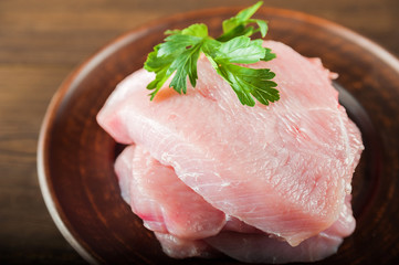 Chicken fillet on a plate on the background of a textural wooden table. Turkey fillet close up and copy space