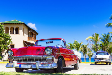 Roter amerikanischer Cabriolet  Oldtimer und ein blau weisser Oldtimer parken am Strand von Varadero in Cuba - Serie Kuba Reportage