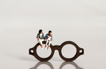 Miniature people and miniature glasses. A concept about social views on female couples families.