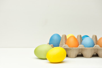 Painted easter eggs in the box on wooden background, close up view