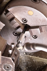 Spindle chuck and installed metal part in pocessing on high precision Cnc industrial lathe turning machine. CNC machine drills a hole in a metal part. Close up