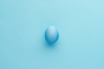 Painted blue egg on blue background, monochrome view