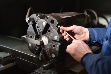 A worker in blue workwear performs maintenance on the CNC machine to install drills in the turret...