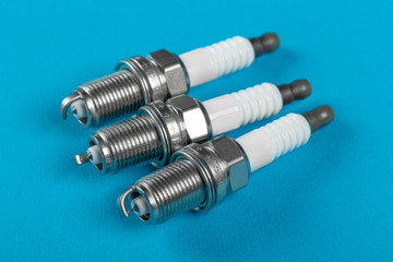 A set of new spark plugs a blue background.
