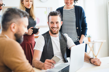 Group of young businesspeople with laptop working together in a modern office.