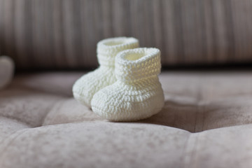 Homemade baby booties on the background of the sofa