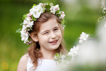 Beautiful young girl in white dress in the garden with blosoming  apple trees. Smiling girl  having fun and enjoying