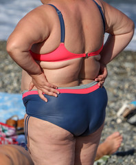 Fat woman in swimsuit on the sea beach