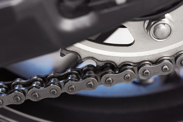 Closeup detail of sport racing motorcycle rear drive o-ring chain and sprocket power transmission from the engine to wheel.