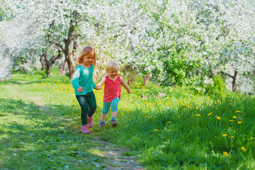 Fototapeta premium happy girls play run in spring nature, kids enjoy apple blossom