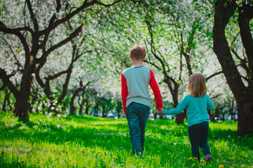 little boy and girl wak in spring nature, kids enjoy apple blossom