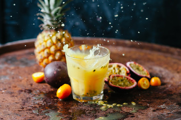 Glasses of juice with tropical fruits on the table on a dark background