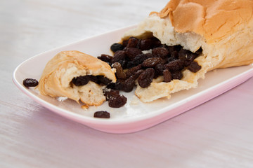 Raisins bread on the plate put on white color paint wood floor