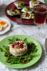 Healthy nutritious lunch or dinner for two: grilled camembert with grains of pomegranate, a branch of rosemary and nuts on a cushion of arugula. 