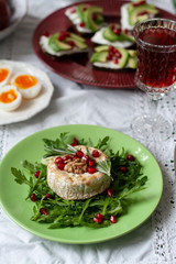 Healthy nutritious lunch or dinner for two: grilled camembert with grains of pomegranate, a branch of rosemary and nuts on a cushion of arugula. 