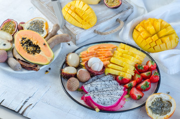 Many kinds of tropical fruits on white table. Mangosteen, lychee, tamarind, cherimoya, granadilla, mango, passion fruit, rambutan, strawberry, papaya.