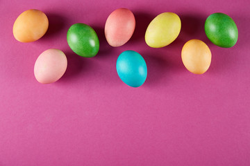 Bunch of blank painted Easter eggs of different pastel color on bright crimson paper background with a lot of copy space for text. Top view, flat lay, close up.