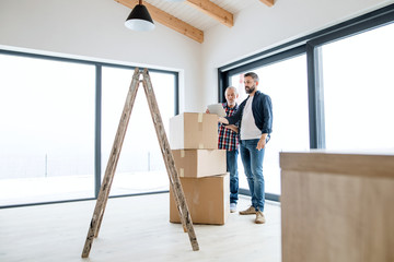 A senior man helping his son with furnishing new house, a new home concept.