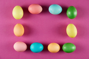 Bunch of blank painted Easter eggs of different pastel color on bright crimson paper background with a lot of copy space for text. Top view, flat lay, close up.