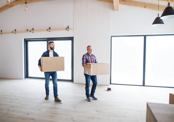 A senior man helping his son with furnishing new house, a new home concept.