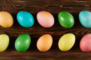 Bunch of blank painted Easter eggs of different pastel color on dark wooden table background with a lot of copy space for text. Top view, flat lay, close up.