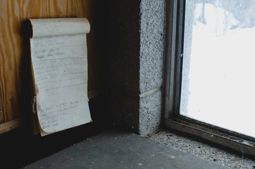 A old paper to do list on the old shelf in the garage work shop next to the cold window. 