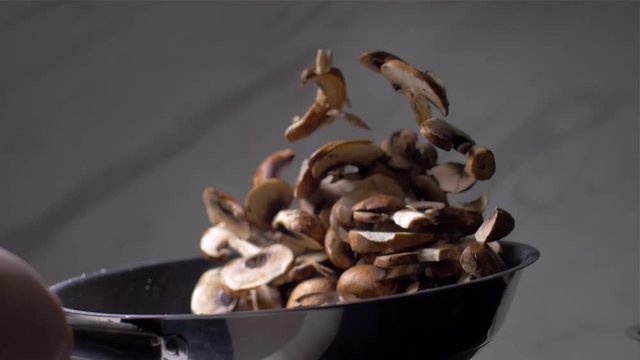 Chef throws mushrooms in a pan