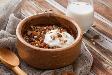 Homemade granola with nuts, raisins and yogurt in a wooden bowl