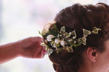 Obraz na płótnie Canvas A bride at hairdressing salon making wedding headdress. A hand touching a hair of bride