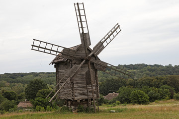 Fototapeta na wymiar Wooden old windmill on field in summer in Ukraine Pirogovo