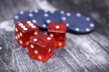Red dice and casino gaming chips on vintage wooden table. Background for casino games, gambling, luck or randomness