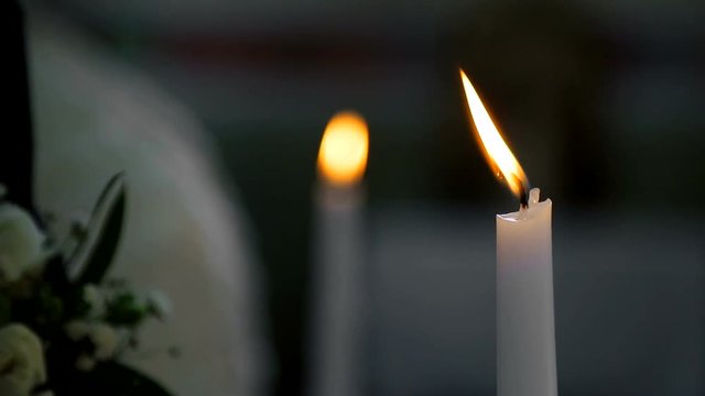 Groom holds a candle in the church. Christianity wedding ceremony. The camera focuses smoothly from one candle to another