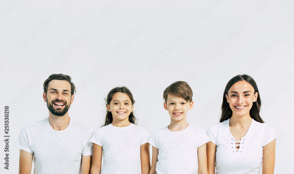 Wall mural Happy and cheerful young beautiful family are smiling and posing while have a fun together over white background