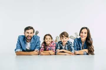 Close up photo of smiling beautiful modern family lying on the floor and looking on camera