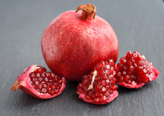 Ripe pomegranates on black stone background