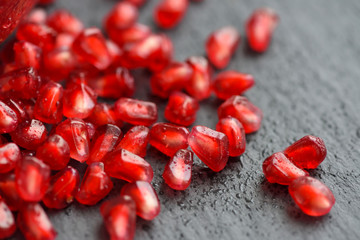 Pomegranate seeds over black stone background