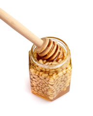 Fototapeta na wymiar A honey jar with pine nuts and a spoon for honey on white background
