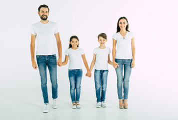 Obraz premium Happy and cheerful young beautiful family are smiling and posing while have a fun together over white background