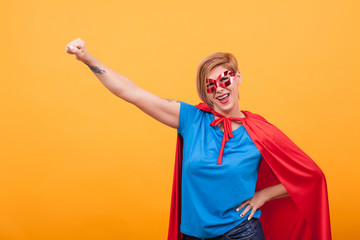 Young woman dresed like superheros flying off to save the world over yellow background