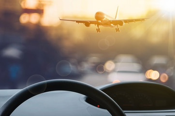 Inside car view ,steering wheel and airplane on blur traffic road with colorful bokeh light abstract background.