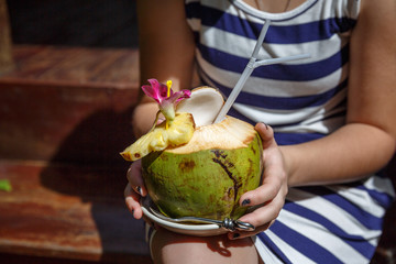 Cropped shot of girl holding coconut cocktail. Sunny day in tropical country. Summer holidays and vacation concept.