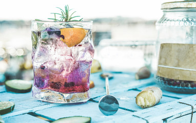 Cocktail with vodka, ginger, orange, fruit berries on blue wood bar counter