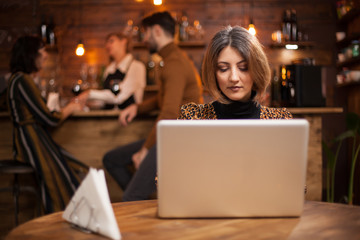 Blonde businesswoman working on her laptop in a coffee shop