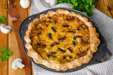 Quiche on puff pastry with leek, meat and mushrooms. Rustic style.