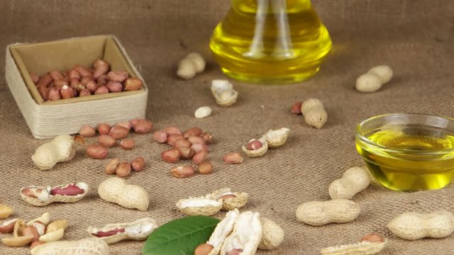 Groundnut oil in a glass bottle and a bowl on the background of peanut and parts of the peanut