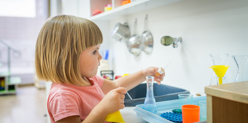 Cute caucasian child girl performs experiment in kindergarten