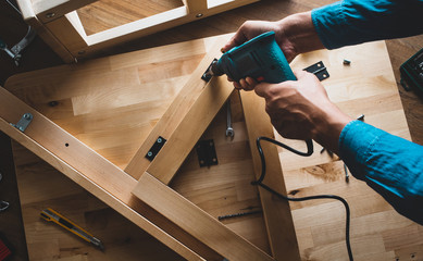 Carpenter man working with drill and furniture,fixing or repairing house.modern living concepts